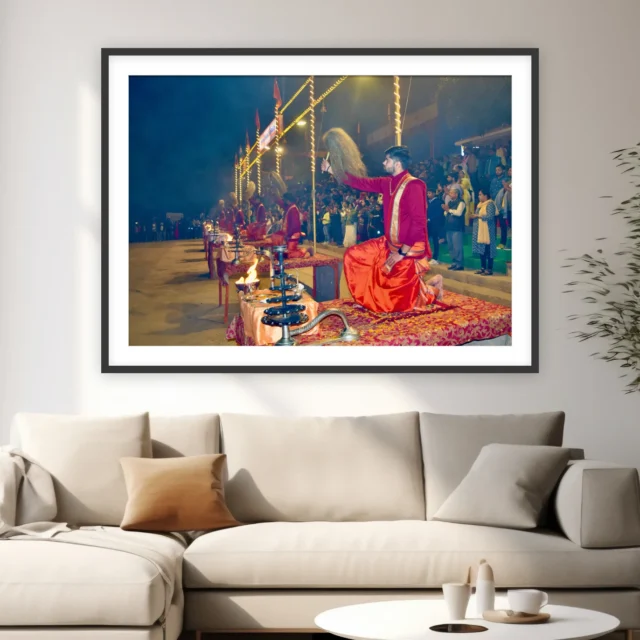 Photograph of a kneeling priest raising a chamar at the Ganga Aarti in Varanasi with lamps and crowd behind